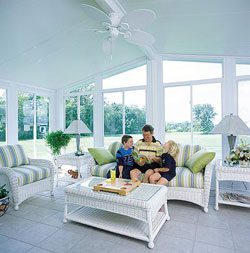A family sitting on the couch in their sunroom.